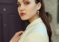 a woman in a white jacket and earrings