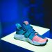 blue, pink, and white adidas athletic shoe on white display table