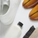 a pair of white shoes next to a white shoe brush